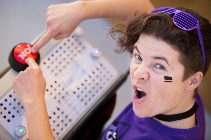 Aśka in a purple shirt pressing a big red NO button