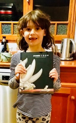 Girl in striped shirt holding up the book