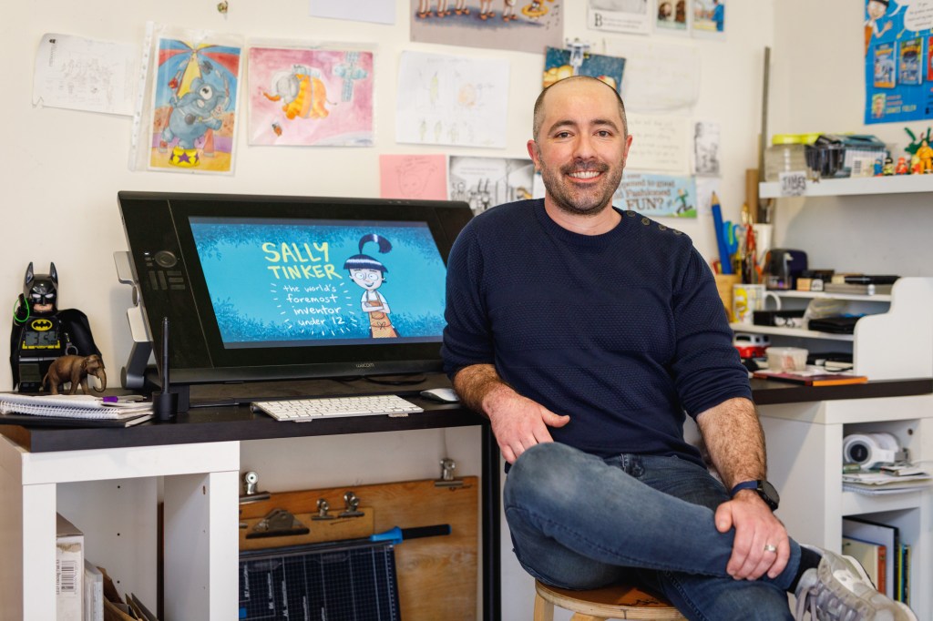 James Foley sitting alongside his desk and wacom. Photo by Jessica Wyld Photography.