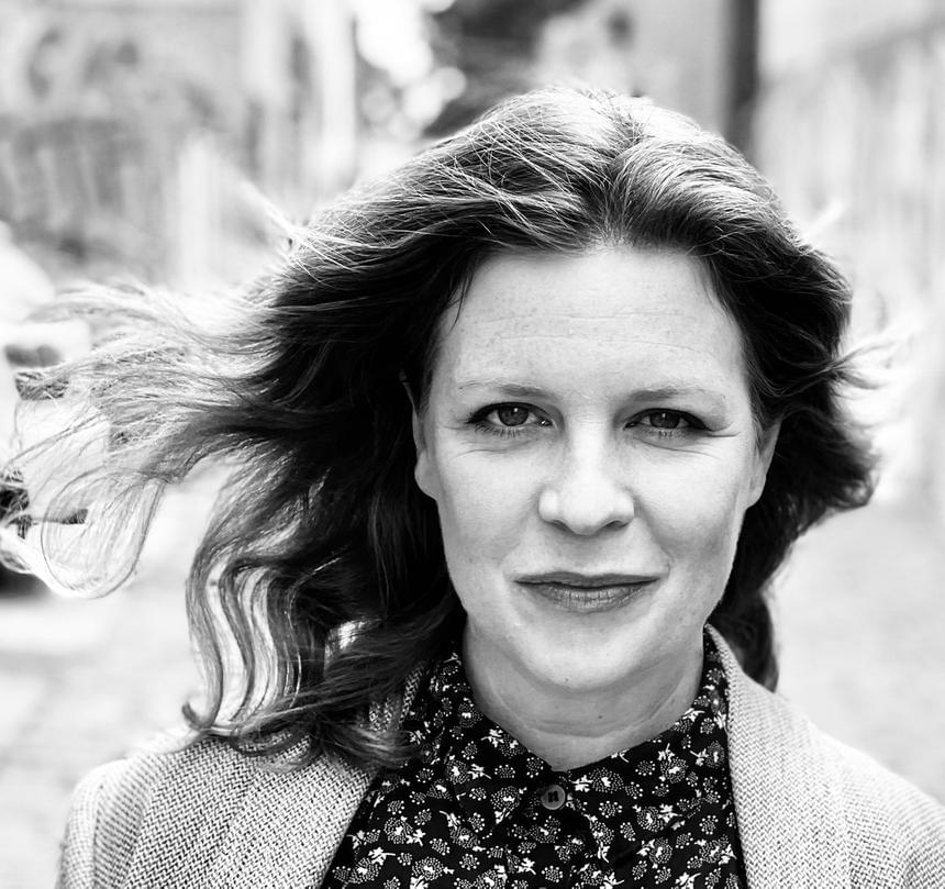 A head and shoulders photo of a woman with hair blowing in the wind