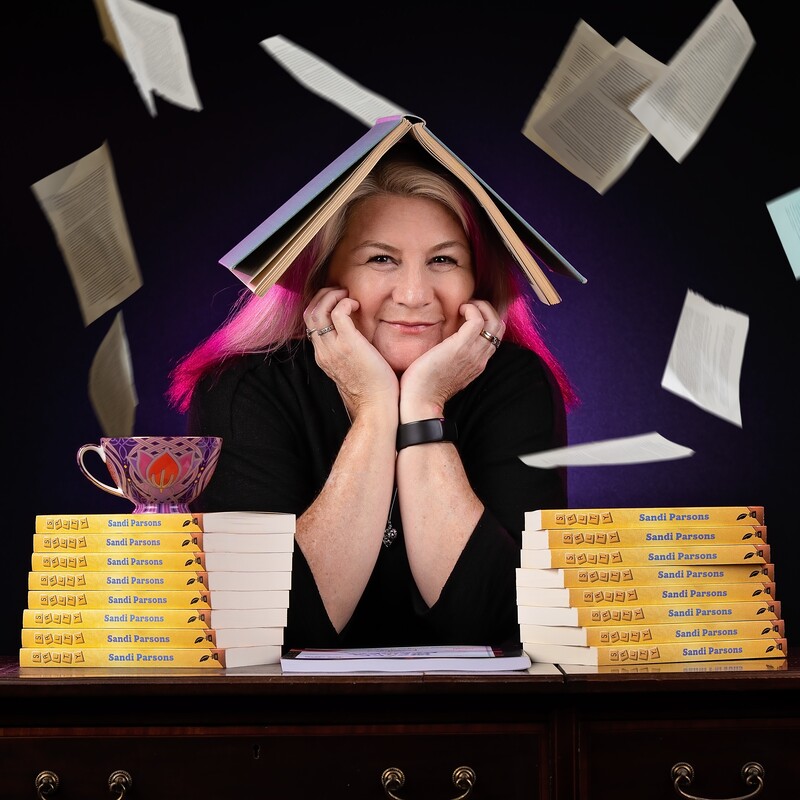 A photo of Sandi Parsos surrounded by books.