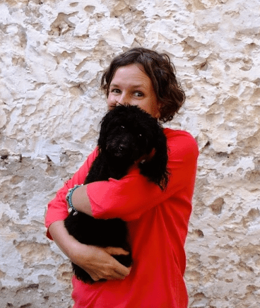 HM Waugh cuddling a small black 'oodle' dog