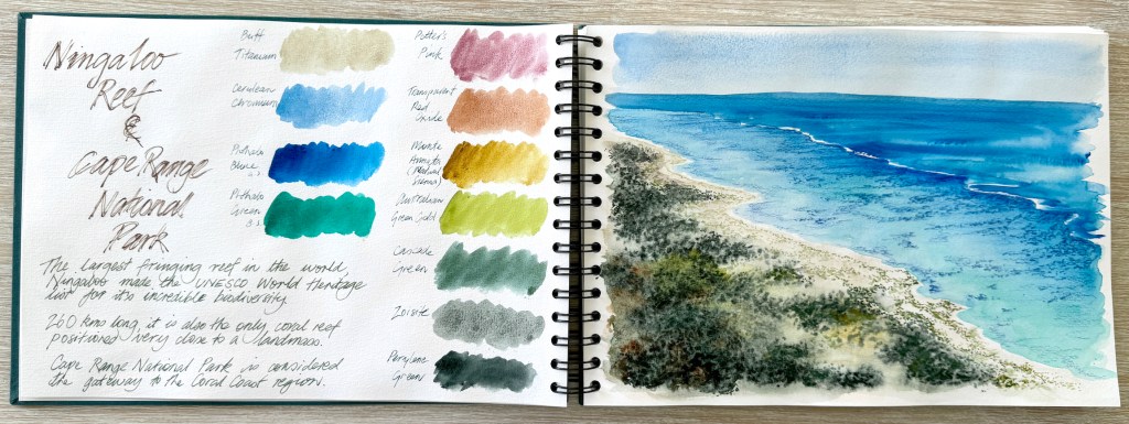 A wirebound art journal lying open to show watercolour swatches on the left page, and handwritten notes and observations. The right hand page shows a watercolour painitng of the ocean and sand and weed.